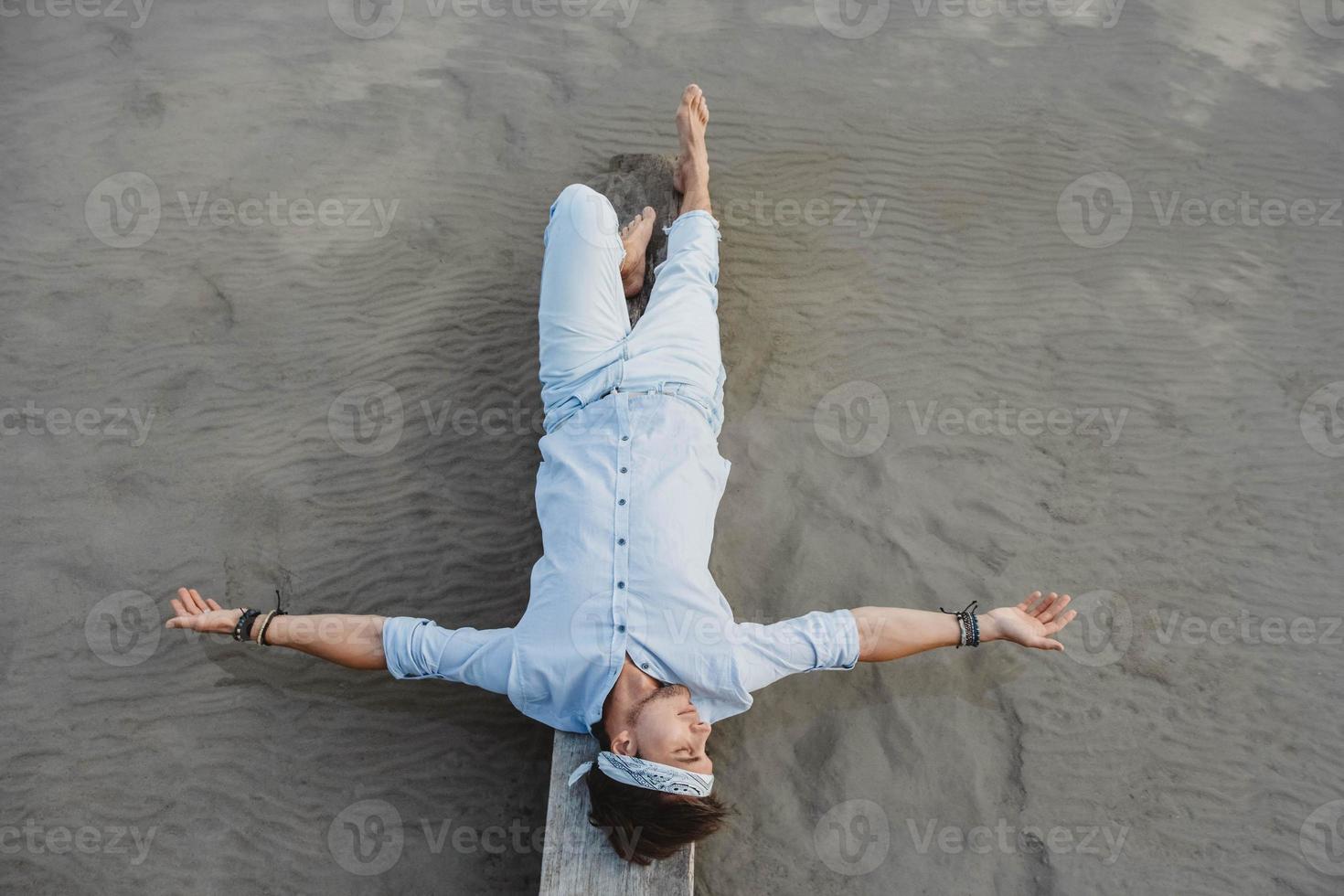 Mann liegt auf Holzbrücke vor dem Hintergrund von Wasser foto