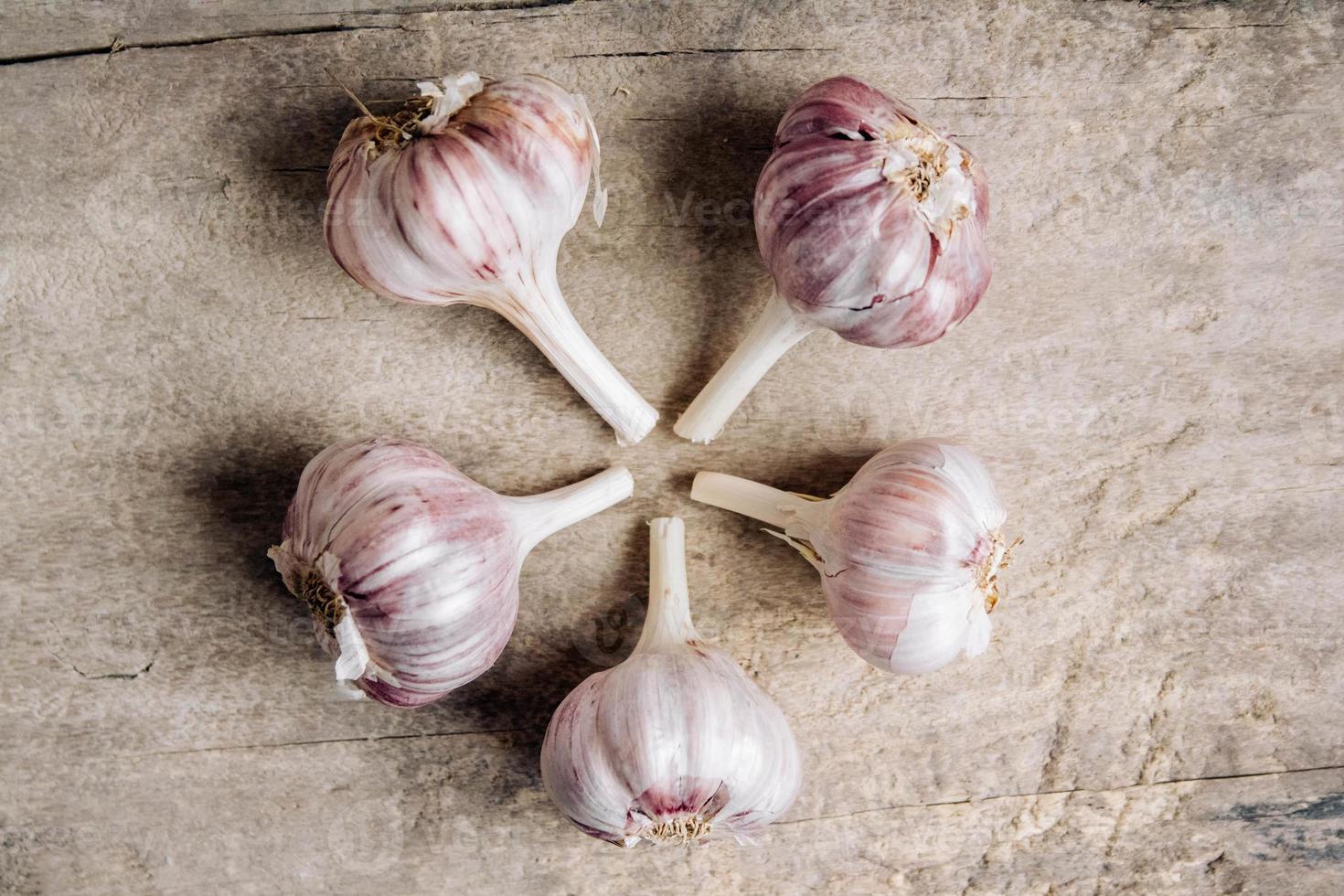 Knoblauch liegen in einer Reihe auf einem rustikalen Holzhintergrund foto