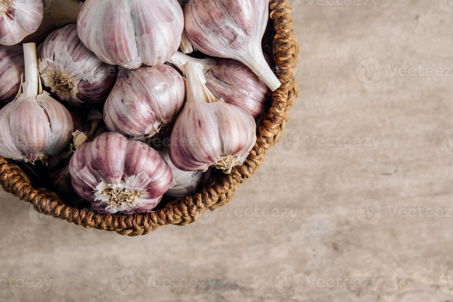 Knoblauch in einem Weidenkorb auf einem Holztischhintergrund foto