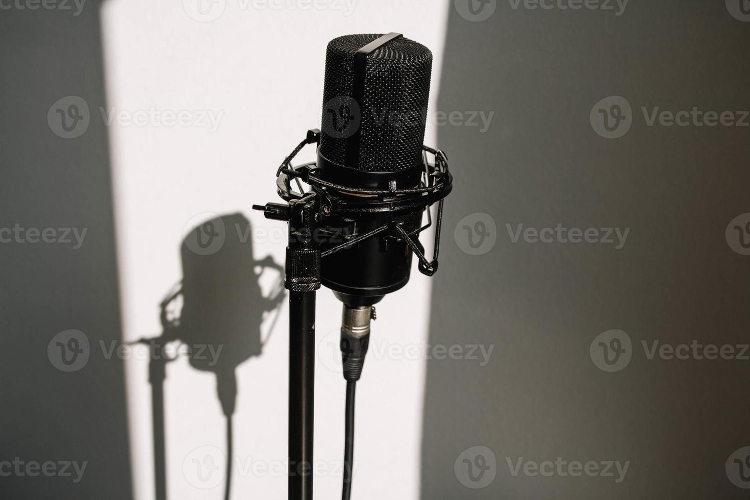 professionelles Studiomikrofon auf einem modernen Stativ, sehr praktisch und praktisch. weißer Hintergrund mit Schatten an der Wand foto