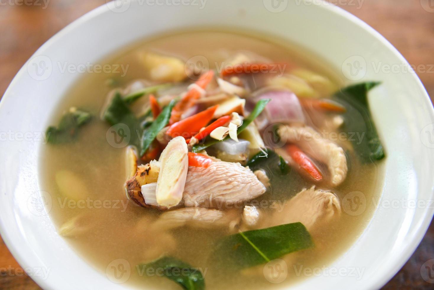 würzige Hühnersuppe - Chicken Tom Yum würziges thailändisches Essen auf weißer Schüssel foto