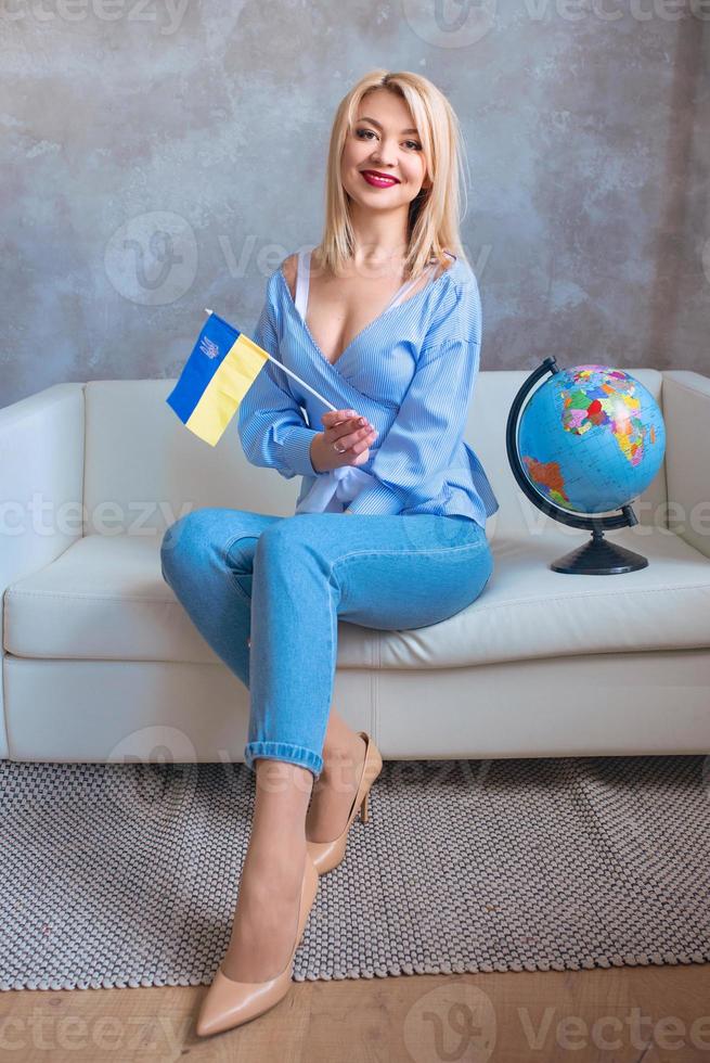 schöne attraktive fröhliche blonde slawische Frau mit Globus und ukrainischer Flagge. foto