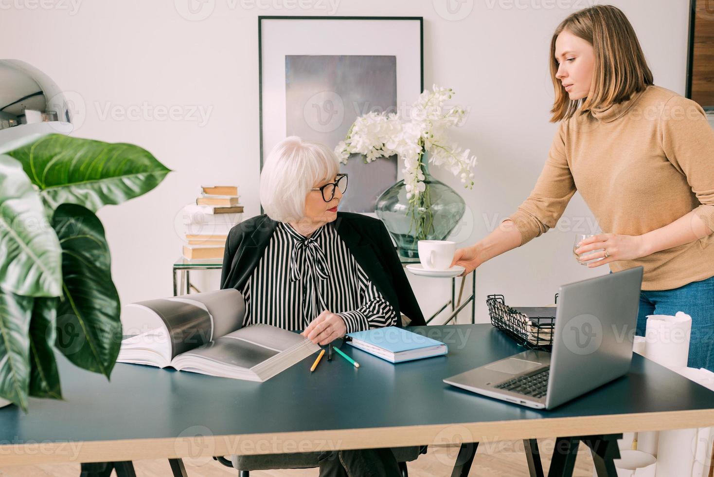 Der junge Assistent brachte dem Chef im Büro einen Kaffee. Geschäft, Kommunikation, Arbeit, Alter, Zusammenarbeit, Mentoring-Konzept foto