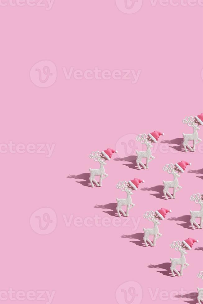 Muster mit glamourösen Rentieren in einer Weihnachtsmütze auf rosa Hintergrund mit Kopierraum foto