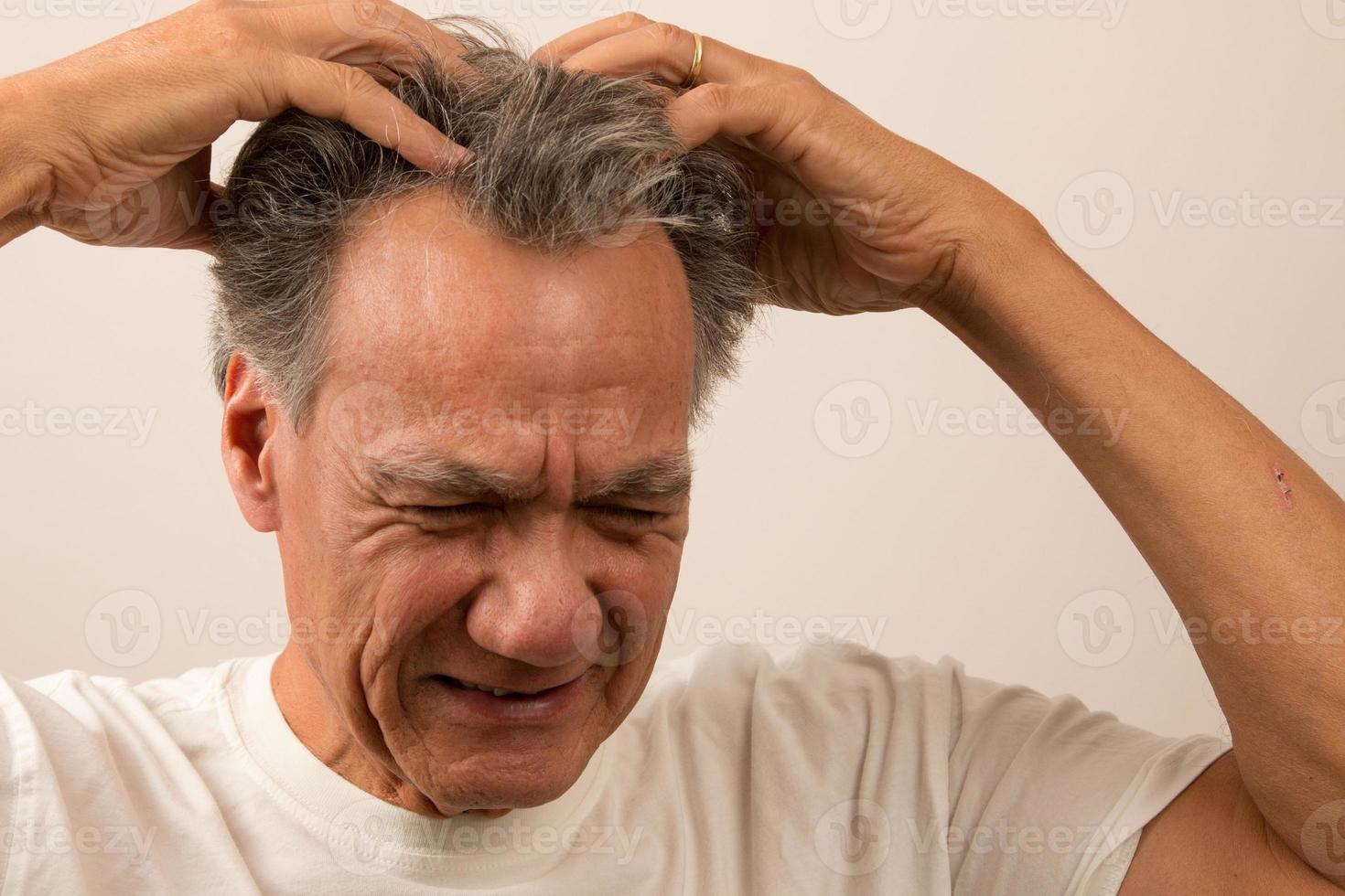 älterer Mann mit Schmerzen und Kopfschmerzen, die sich den Kopf reiben foto