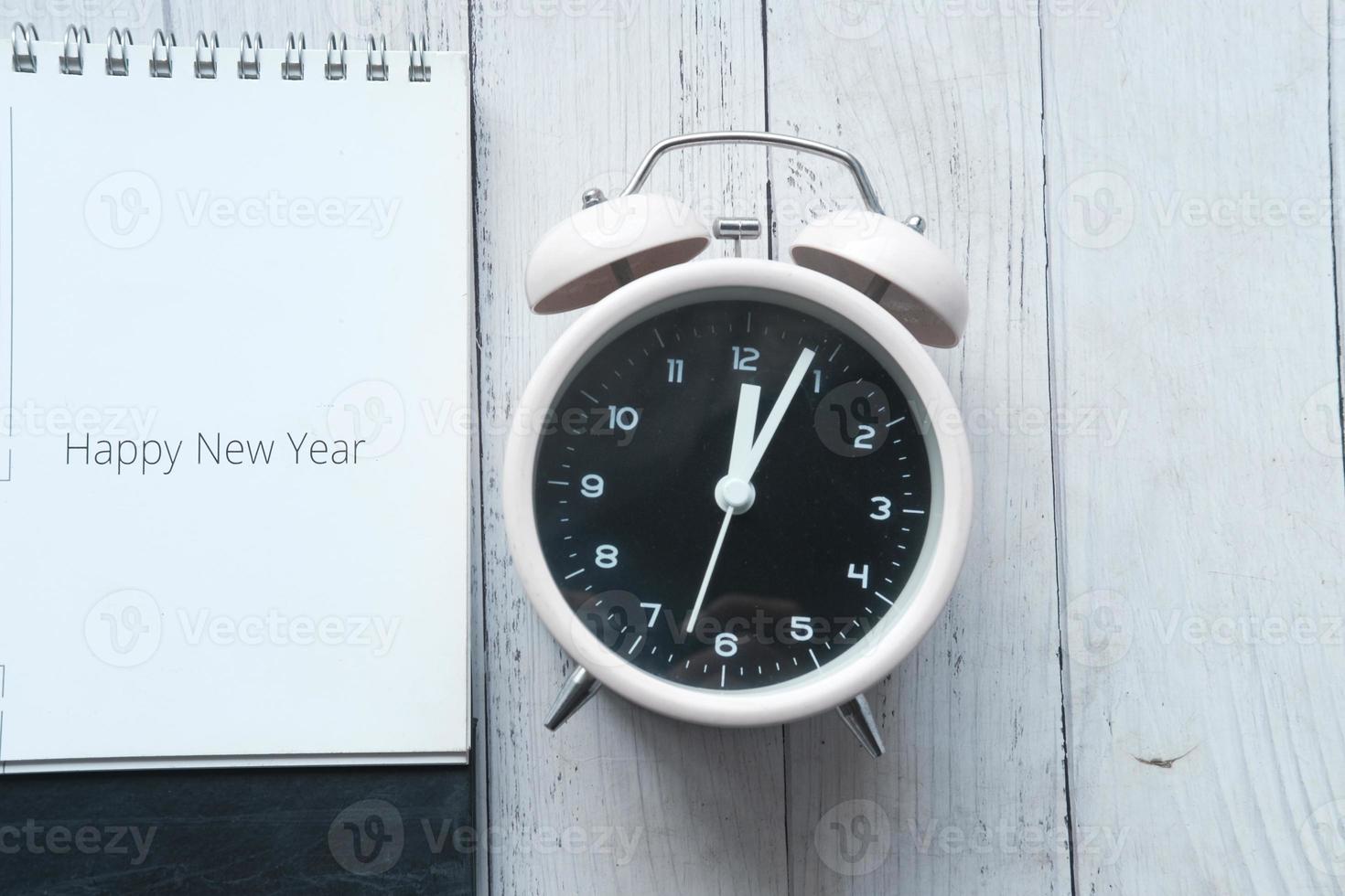Frohes neues Jahr Text im Kalender mit Uhr auf dem Tisch foto