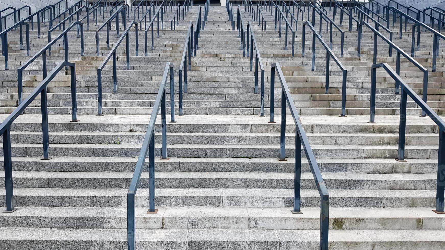 externe mehrstufige Steintreppe. Es gibt viele Treppen und Geländer aus Metall. viele Schritte in einer städtischen Umgebung, symbolischer abstrakter Hintergrund. foto