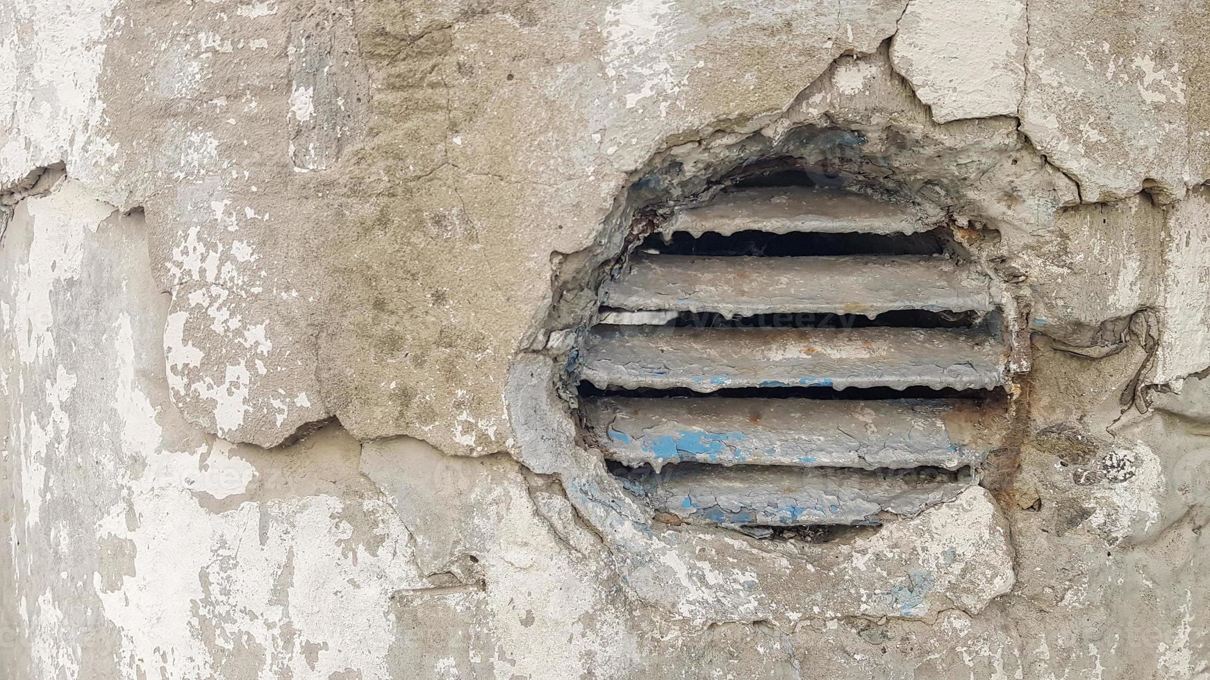 Belüftungsloch im Beton. industrielle runde Lüftungsabdeckung aus Metall. rostiger und schmutziger alter runder lüftungsrahmen mit horizontalen metallstreifen. foto