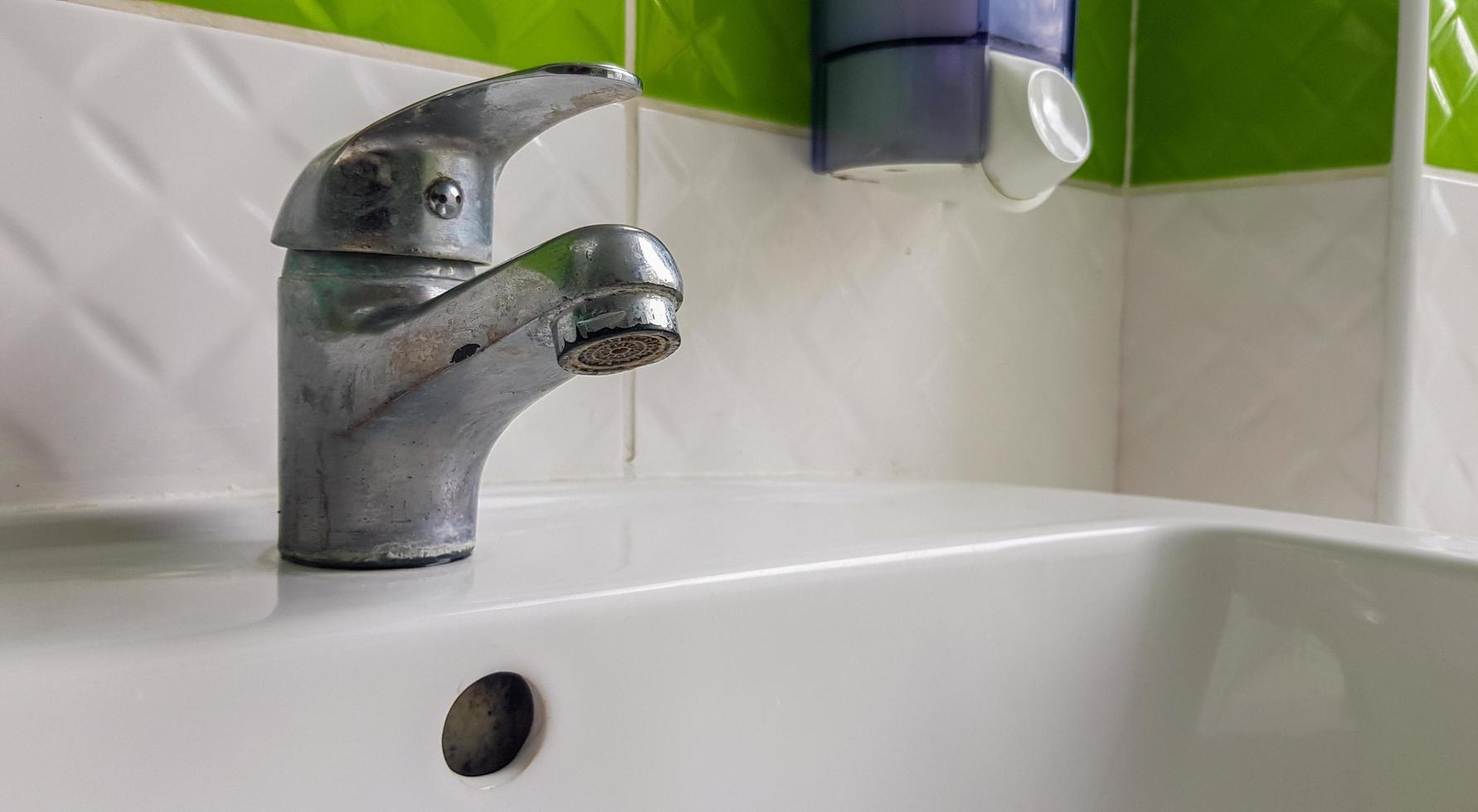 alter Spültischmischer aus Aluminium. Wasserhahn in der Toilette für saubere Hände. foto