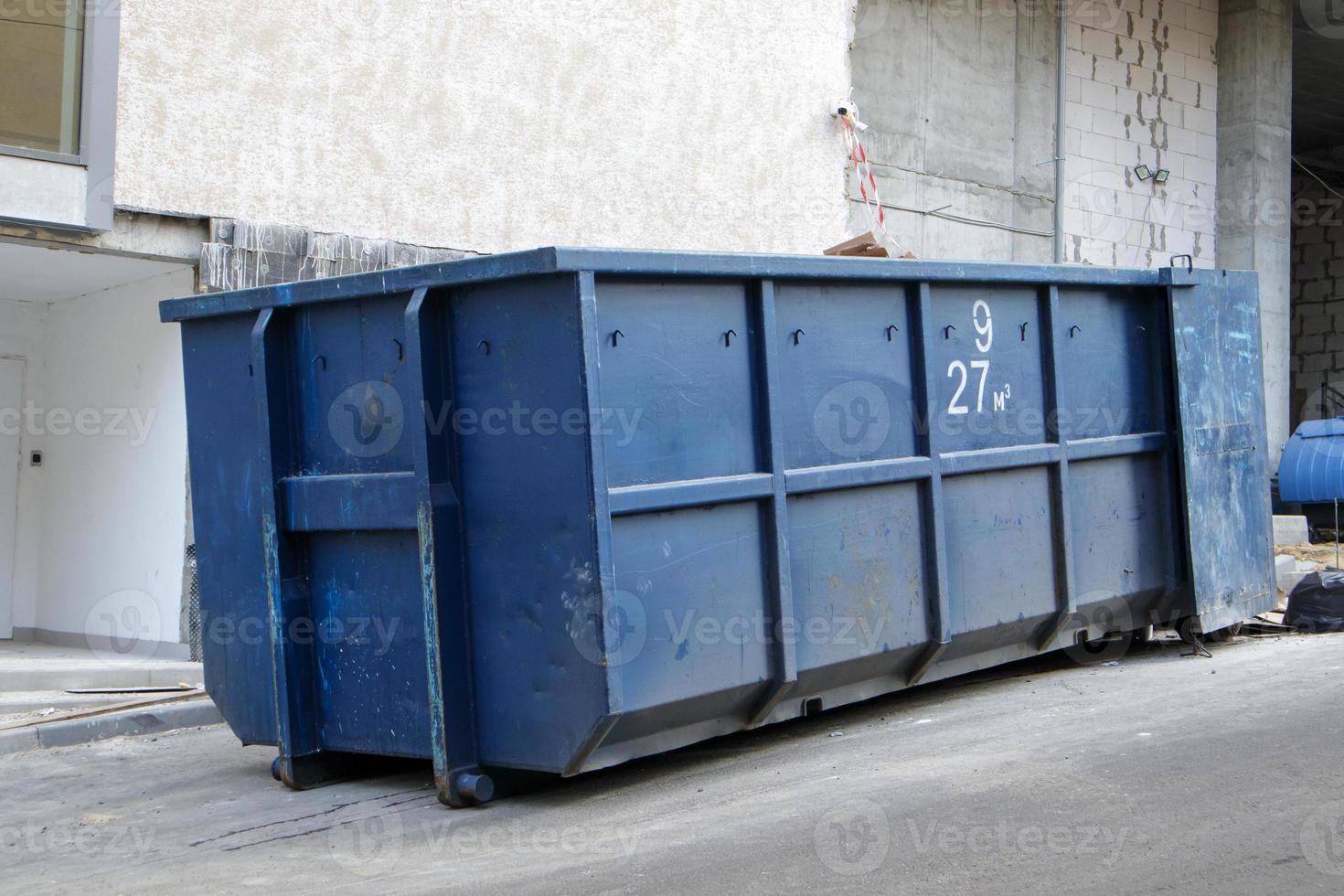 Metall haltbarer blauer industrieller Mülleimer für Müll im Freien auf der Baustelle. großer Abfallkorb für Haus- oder Gewerbemüll. ein Haufen Müll. foto