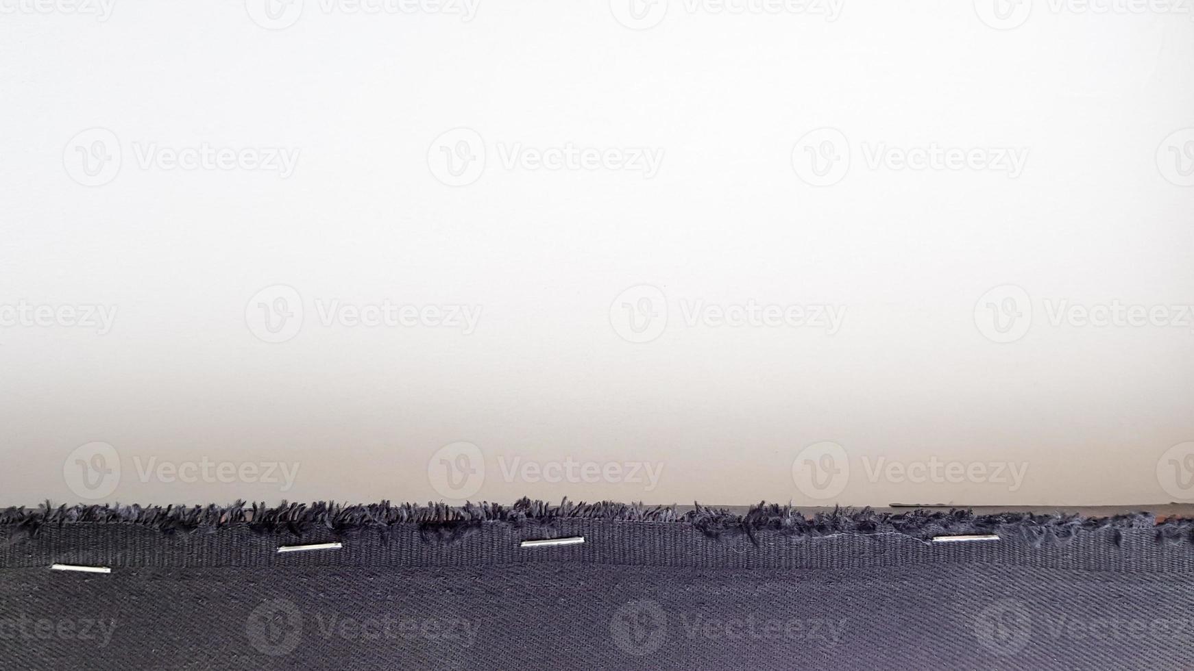 weißer Hintergrund mit einem schwarzen Stoffstreifen, der mit Heftklammern auf ein Holzbrett gestanzt ist. abstrakter Hintergrund mit Kopienraum. foto