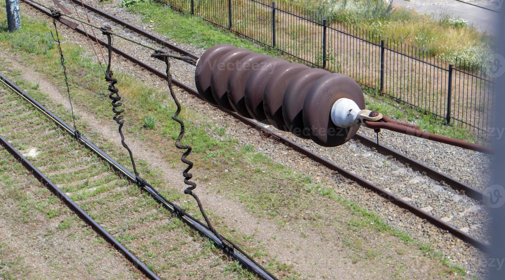 eine Eisenbahn-Oberleitungskomponente entlang eines Gleises mit einem Bahnelektrifizierungssystem, das einen elektrischen Zug mit Strom versorgt. Oberleitungsdraht auf einem Gleis. foto