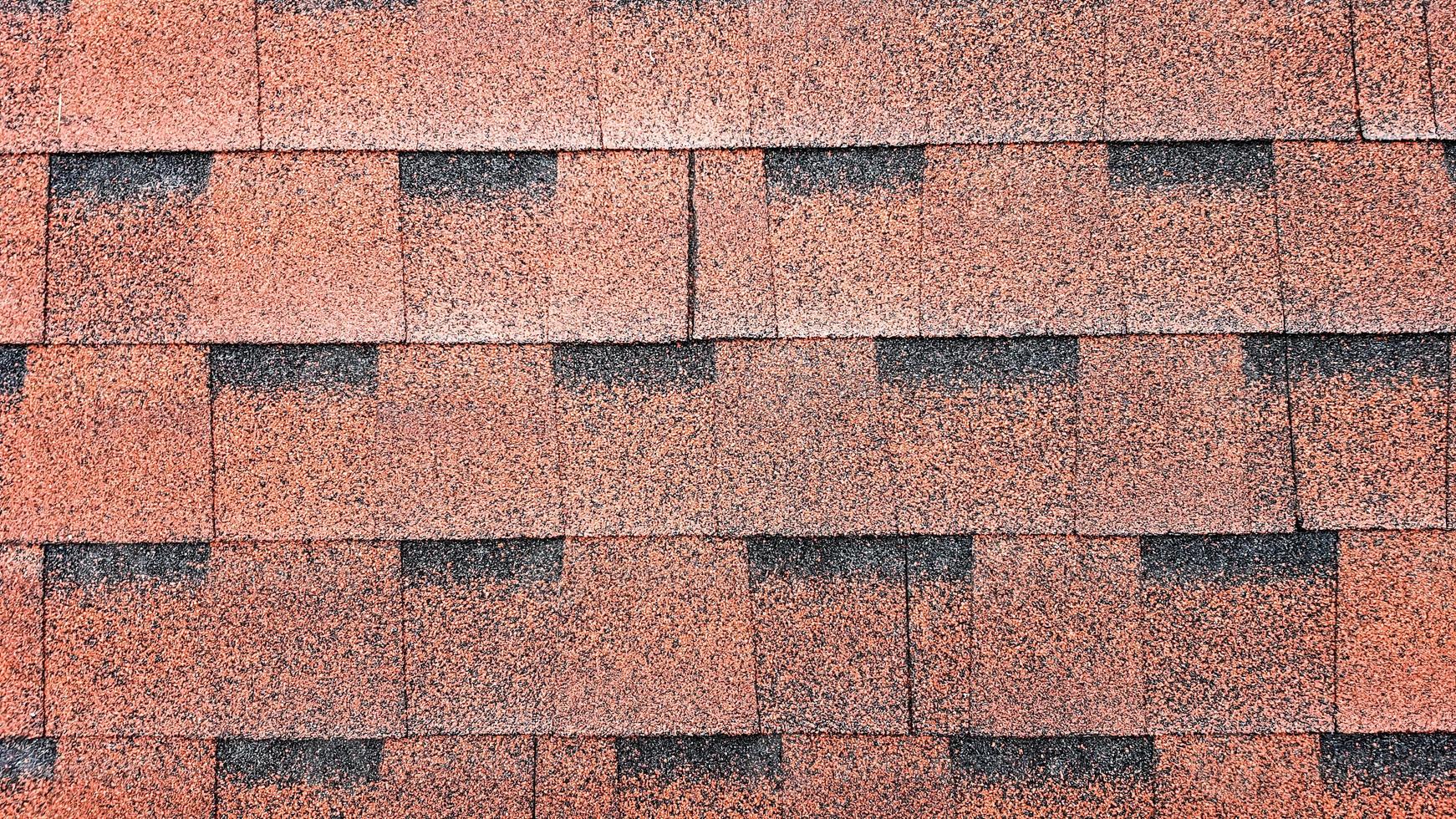 Nahaufnahme auf Asphaltdach rote Schindeln Hintergrund. Dachschindeln aus Bitumen - Dachkonstruktion, Dachreparatur. rote Schindeln auf dem Dach des Hauses. Hintergrund der roten Schindeln foto