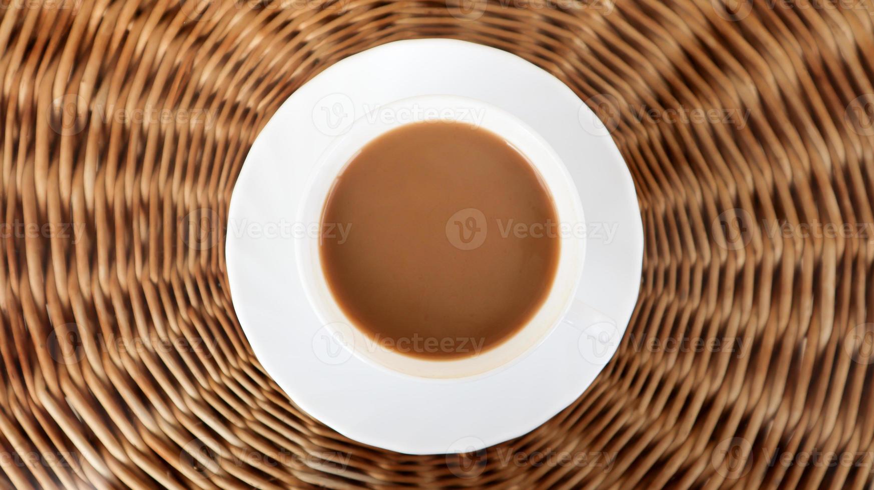 Kaffeetasse auf der Korbweidehintergrundansicht von oben. heißer aromatischer Kaffee mit Milch. frisch zubereitetes Getränk wird in einer modernen Tasse auf einem hellen Korbtisch serviert foto