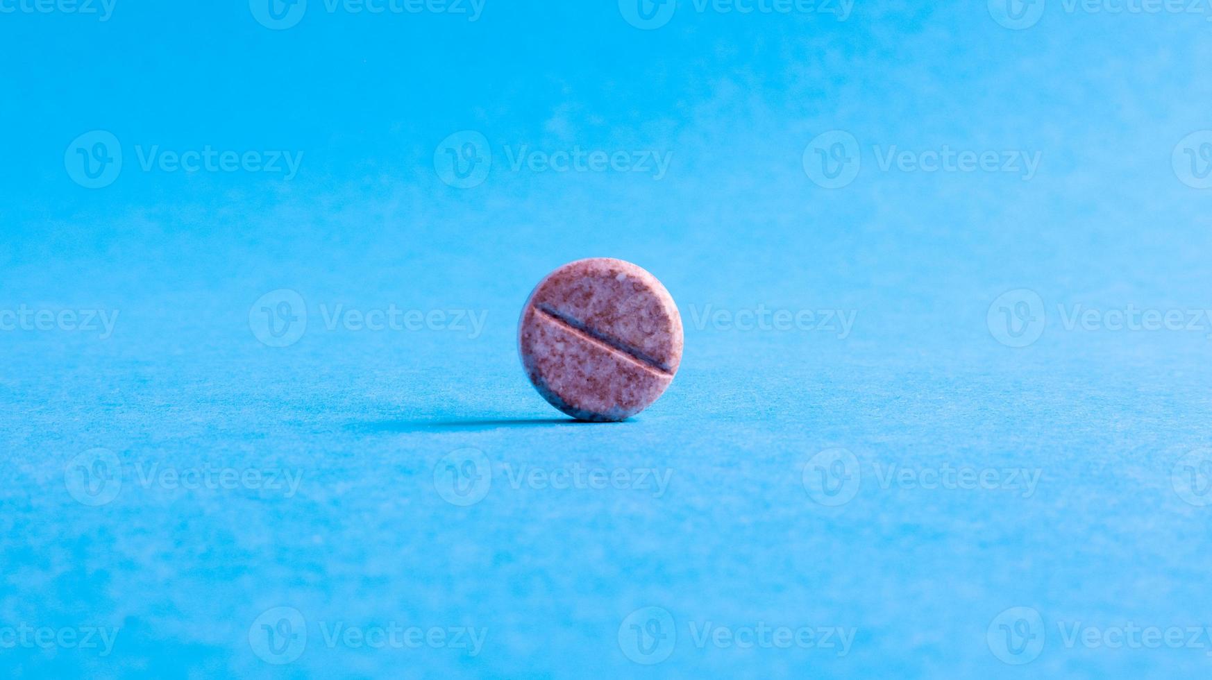eine runde kleine Pille auf blauem Hintergrund in der Mitte mit leerem Platz für Text. foto