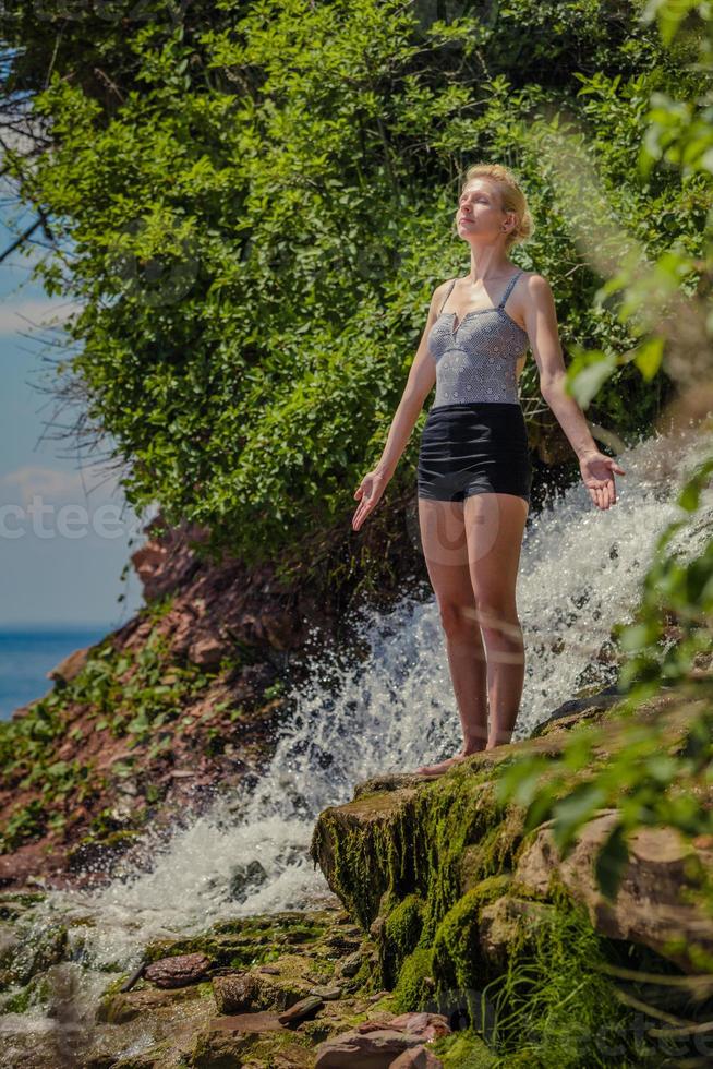 junge Frau macht Yoga-Position in der Nähe eines Wasserfalls foto