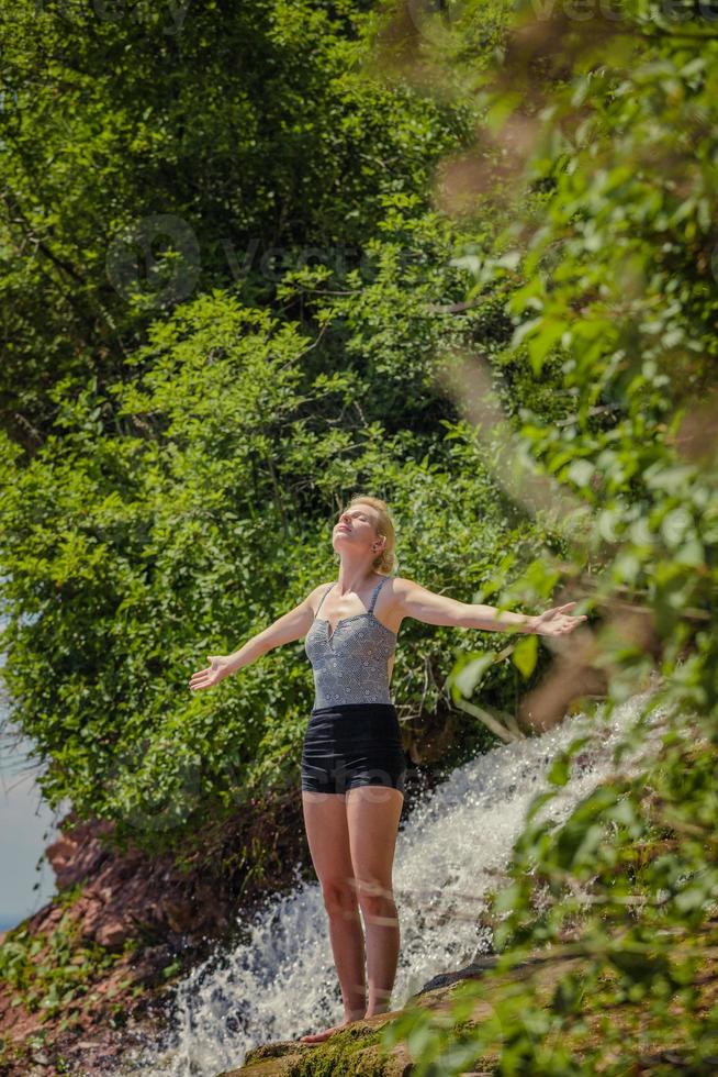 junge Frau macht Yoga-Position in der Nähe eines Wasserfalls foto