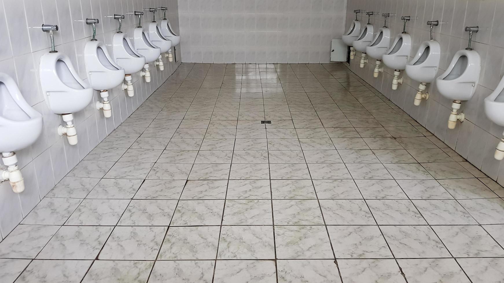 öffentliche Toiletten mit vielen Keramik-Urinalen. große öffentliche Toilette, an der Wand befestigte Schüsseln in der Toilette. Urinale bereiten Schüsseln für Männer vor. foto