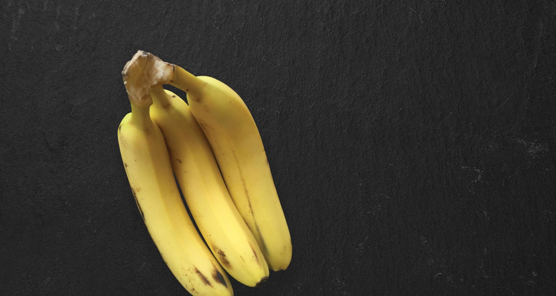 Draufsicht isoliert frische gelbe Bananen auf dunklem Tisch isoliert. Kopierraum für Text hinzugefügt. foto