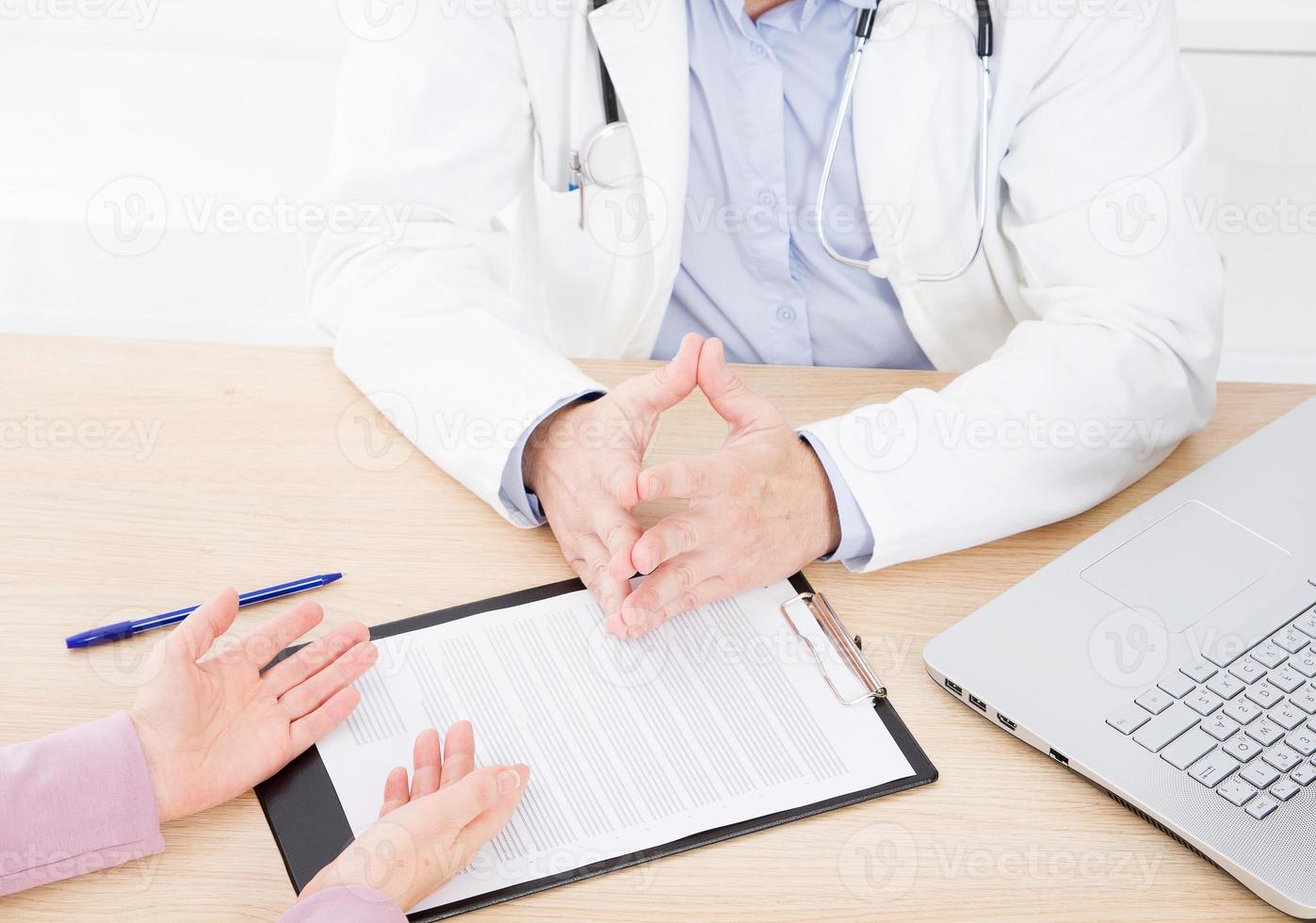 Arzt und Patient diskutieren etwas, nur Hände am Tisch foto