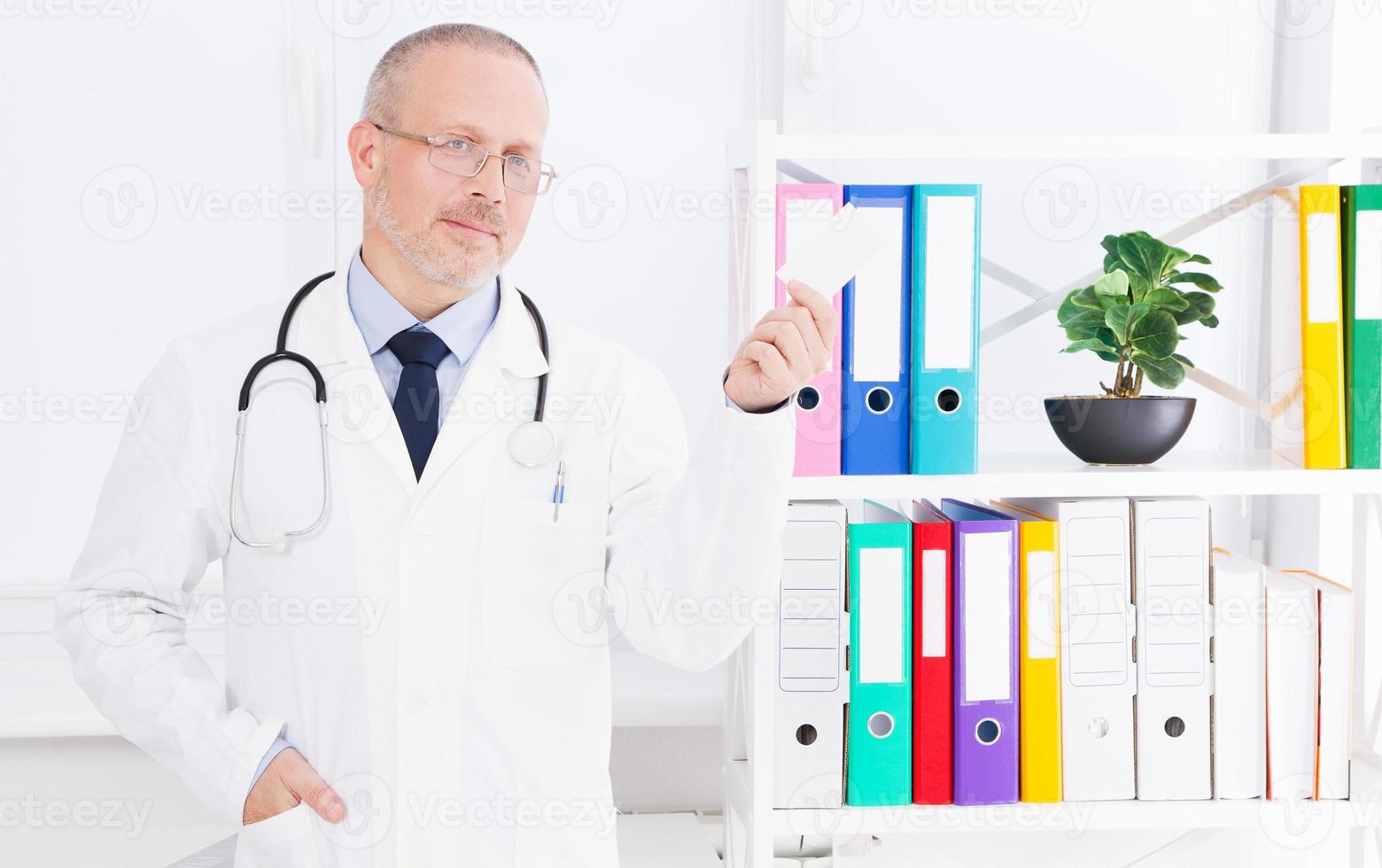 Arzt hält eine Visitenkarte in seinem Büro foto