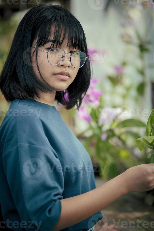 asiatischer Teenager kümmert sich um Orchideenblütenpflanze im Gewächshaus foto