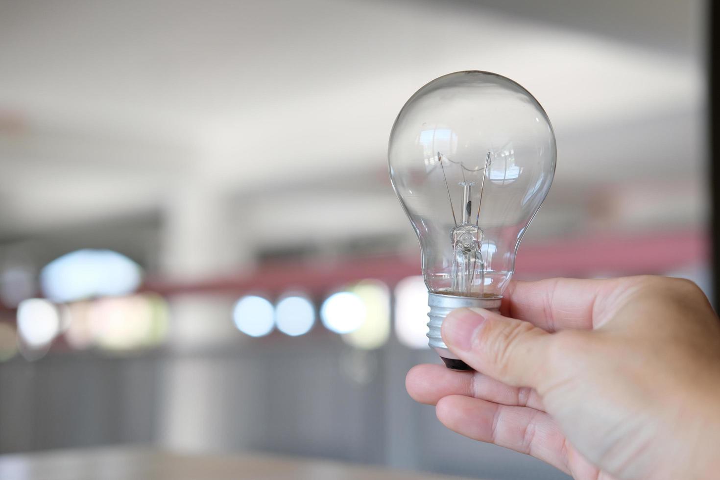 Hand, die eine Glühbirne auf einem Tisch hält, Vorstellung von Ideenkreativität und Inspiration, Zukunftstechnologien foto