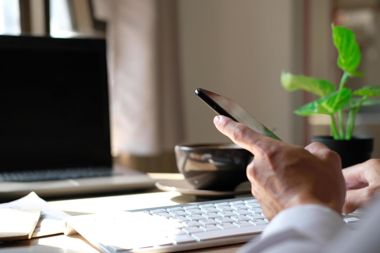 Nahaufnahme der Hände eines Mannes, die mit einem Smartphone aufgenommen wurden, im Café ist ein Mann an seinem Telefon und tippt Nachrichten in sozialen Medien ein. foto