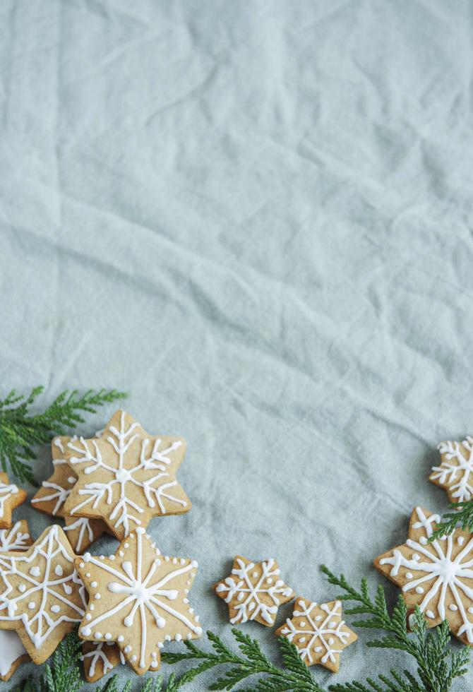 Fichtenzweige mit Weihnachtslebkuchenplätzchen auf dem grünen Leinen zerknitterten Textilhintergrund foto