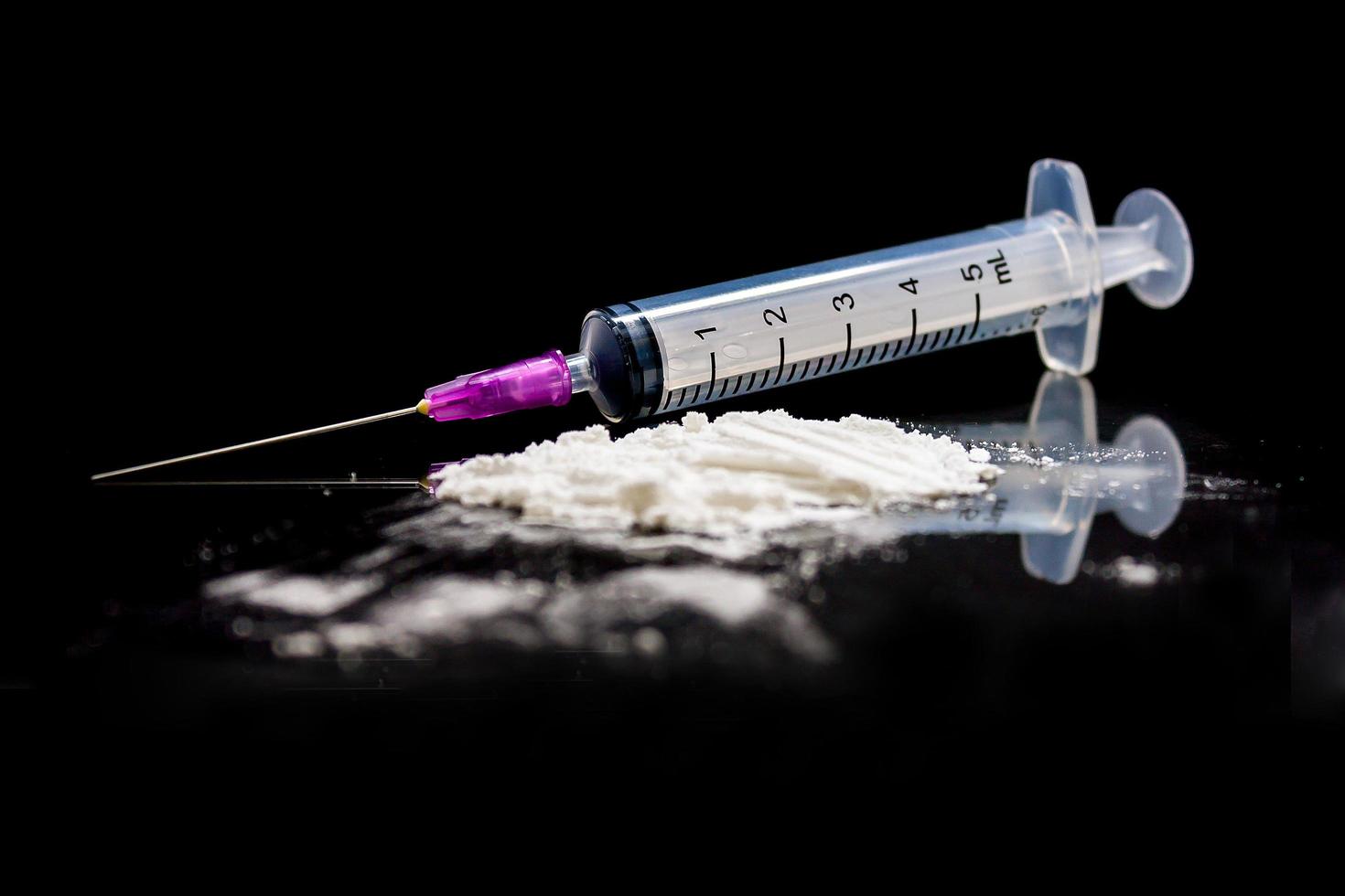 Heroinspritze und gekochtes Heroin auf schwarzem Hintergrund. foto