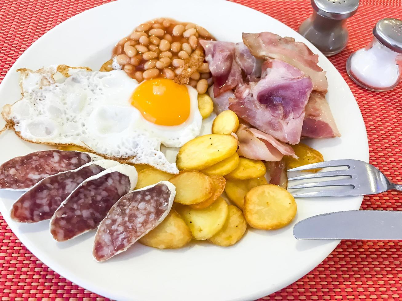 Speck, Bohnen, Spiegelei, Würstchen, Kartoffeln, englisches Frühstück. foto
