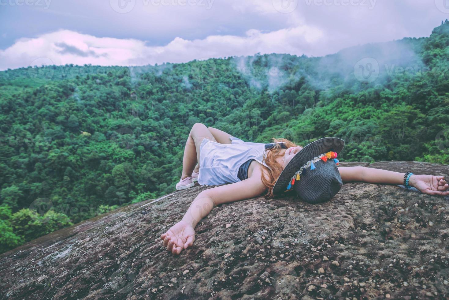 asiatische frauen reisen im urlaub entspannen. schlafe auf einer felsigen Klippe. wildes naturholz auf dem berg. foto