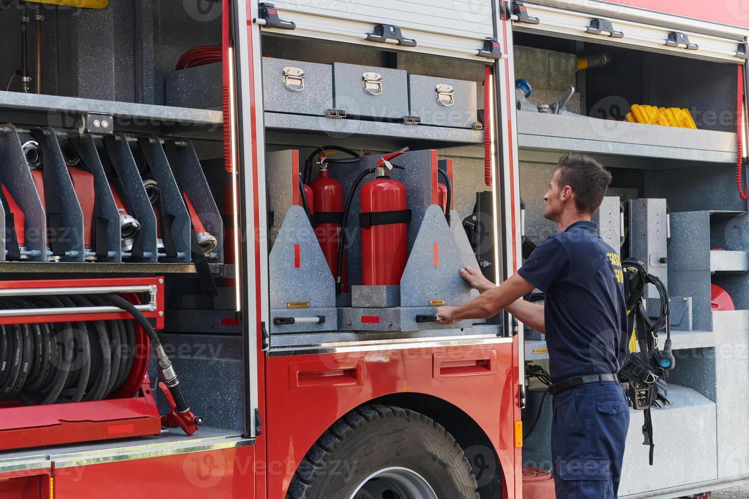 ein gewidmet Feuerwehrmann vorbereiten ein modern Feuerwehrauto zum Einsatz zu gefährlich vom Feuer getroffen Bereiche, demonstrieren Bereitschaft und Engagement zu Notfall Antwort foto