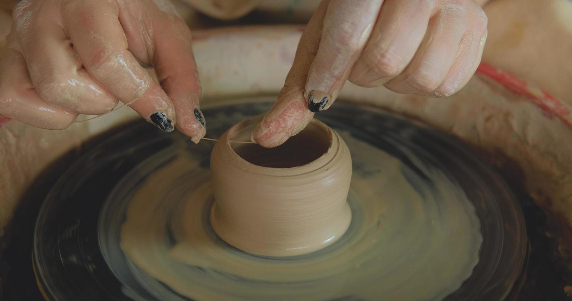 Nahaufnahme von Womans Handarbeit mit Ton im Töpferstudio foto