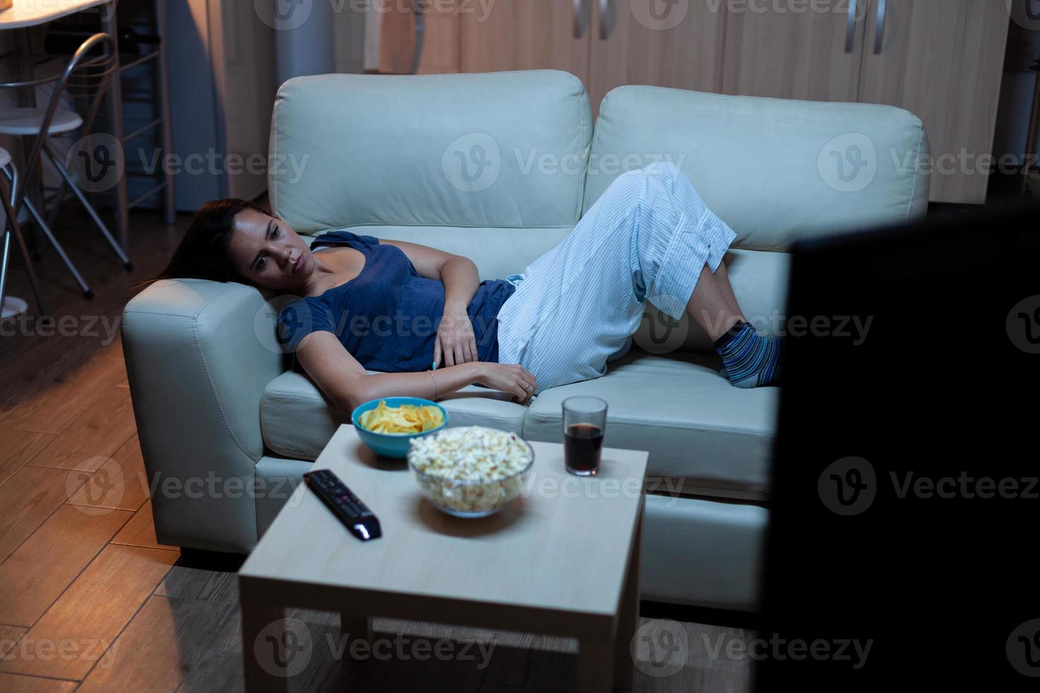 Hausfrau mit Fernbedienung auf der Couch liegend foto