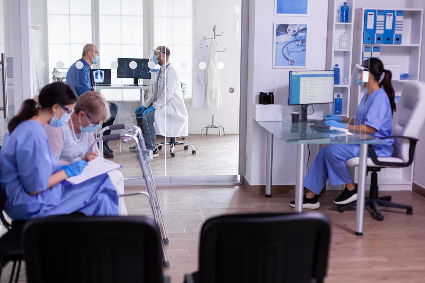 Krankenschwester, die das Terminformular einer alten behinderten Frau mit Gehhilfe überprüft foto