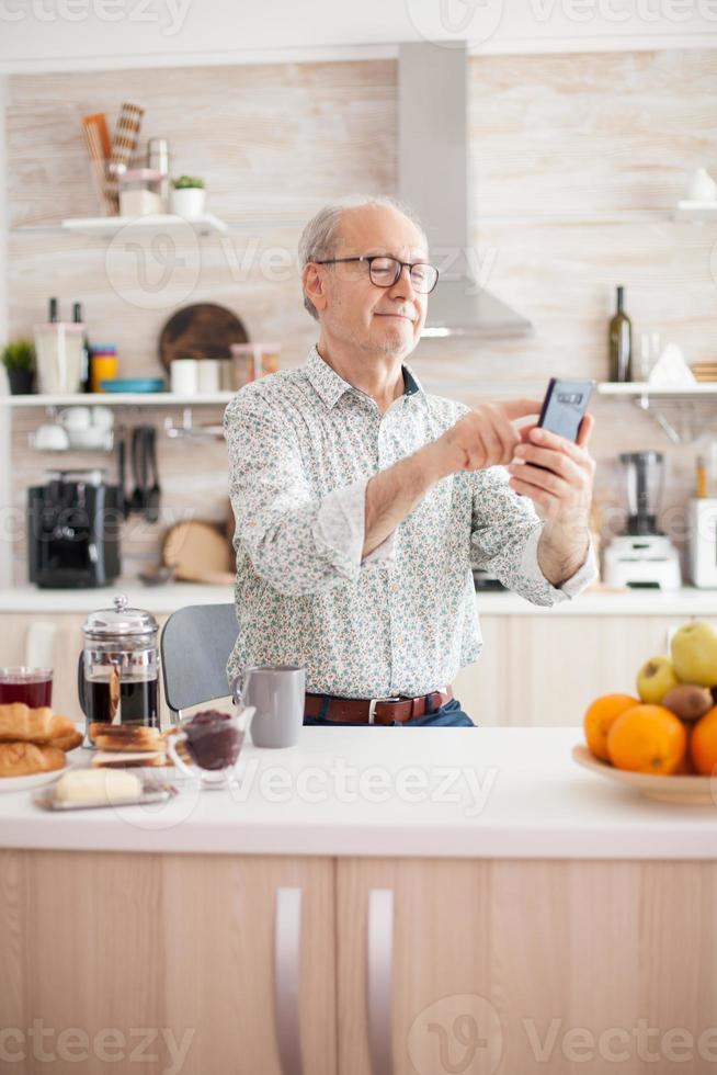 Rentner, der am Telefon scrollt foto