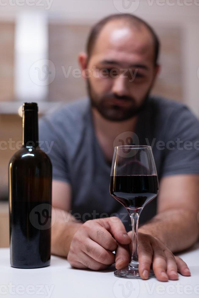 Nahaufnahme von Glas mit Wein für einsamen Mann in der Küche foto