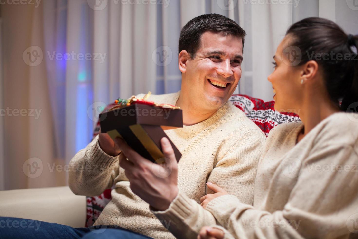 Kaukasischer Mann freut sich über sein Geschenk am Weihnachtstag foto