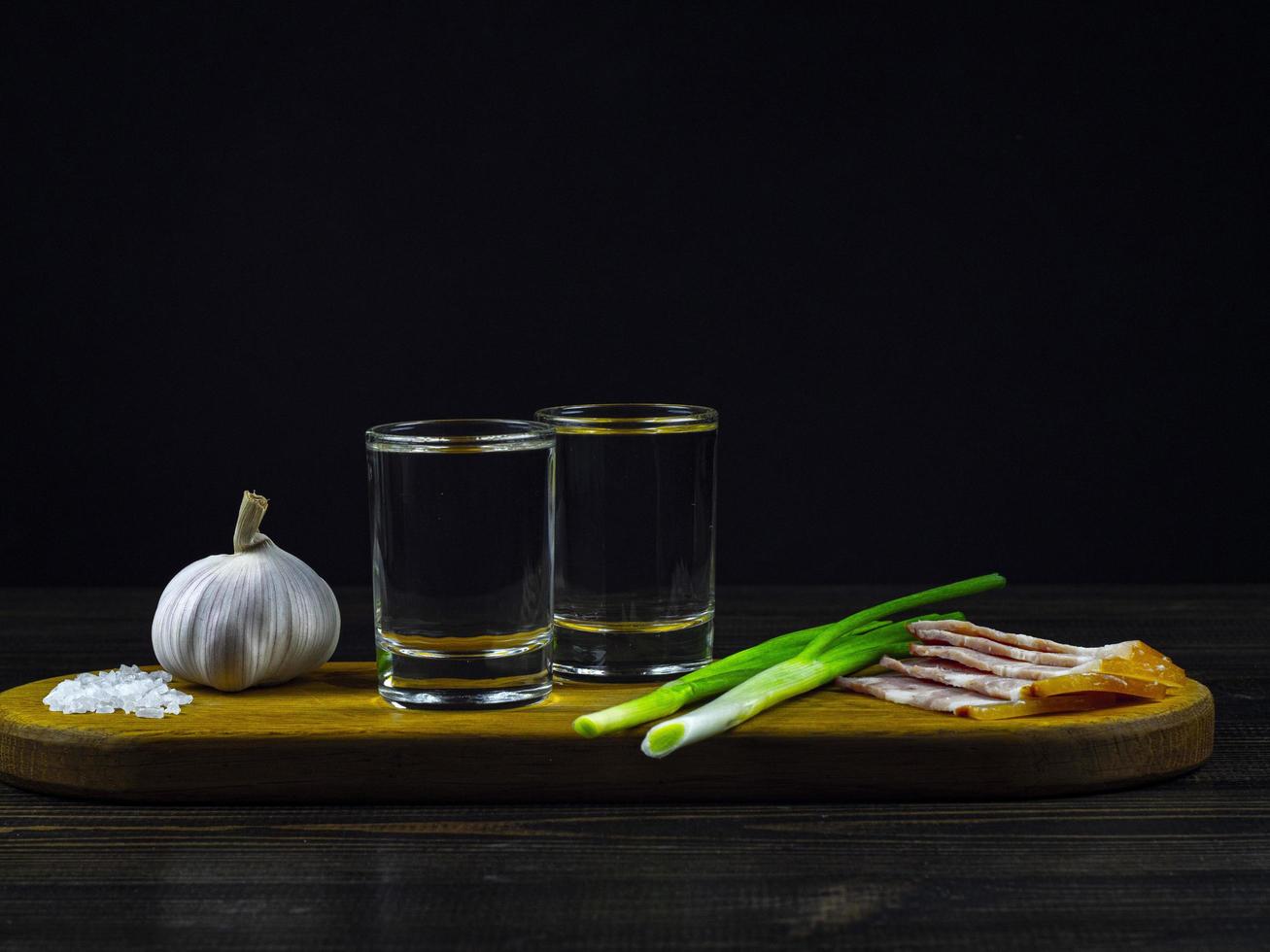 zwei Gläser kalter Wodka mit Zwiebeln, Knoblauch, eingelegten Gurken und Speck foto