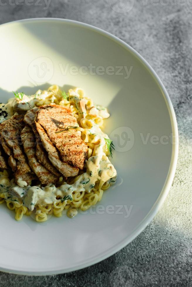 Gericht mit Fleischstücken, Nudeln, Gemüse, Sauce aus Gänseleber foto