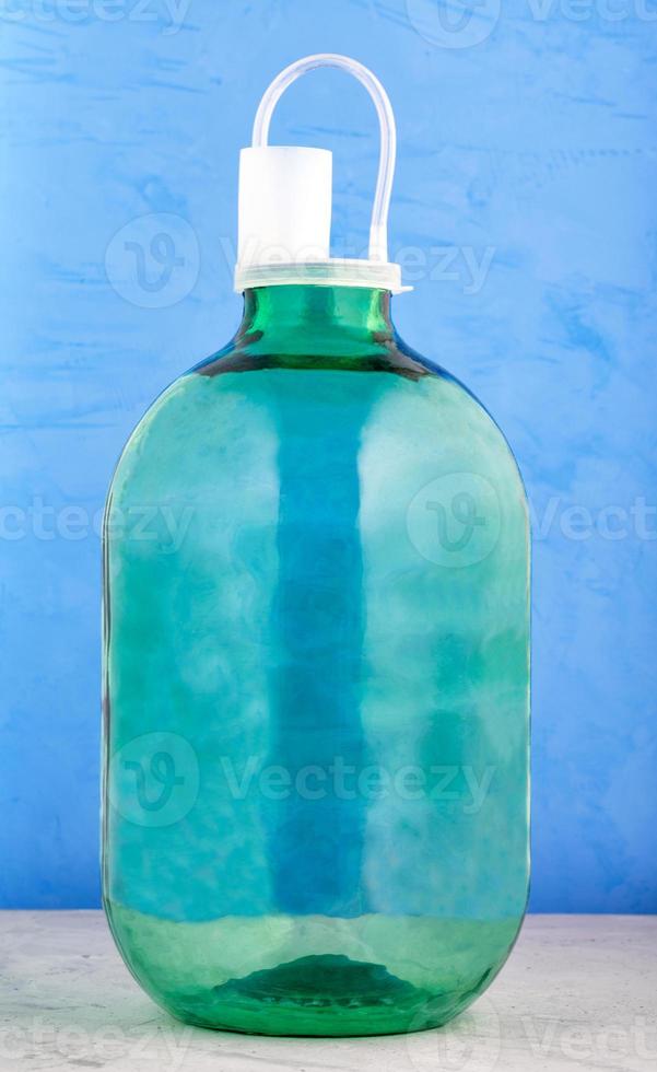 Ein 10-Liter-Glasgefäß besteht aus dickem grünem Glas mit einem Nylondeckel mit Wassersperre auf blauem Hintergrund. foto