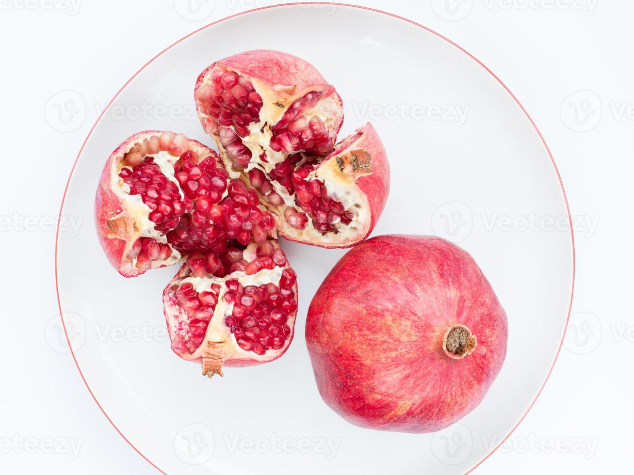 die reife Granatapfelfrucht auf einem weißen Porzellanteller foto