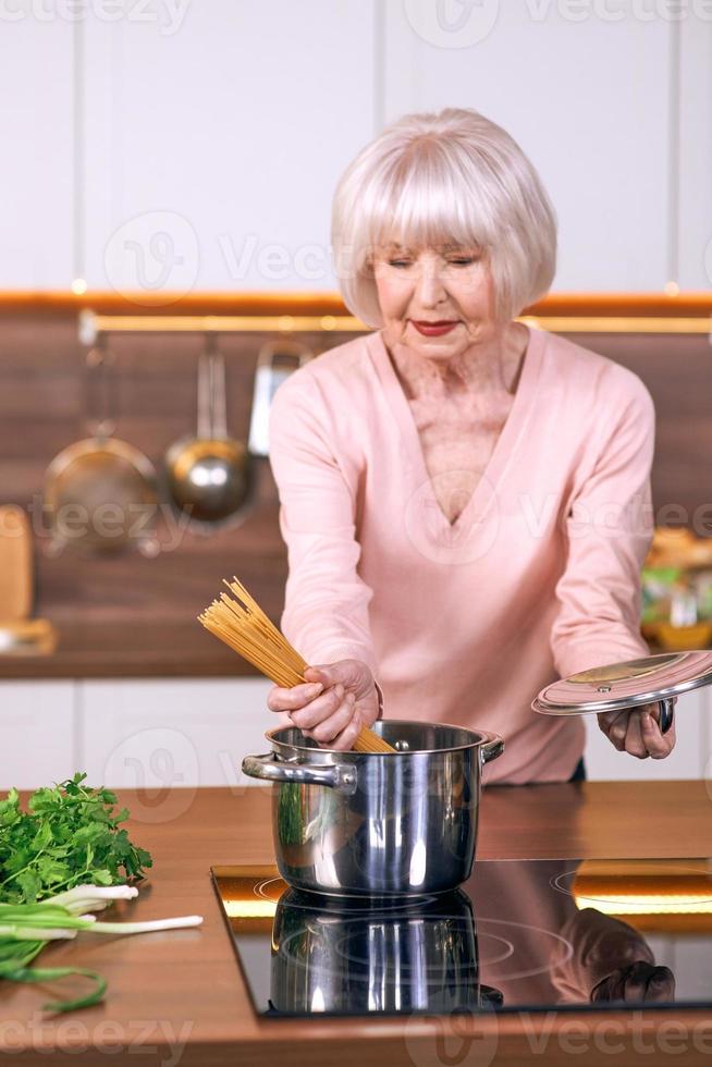 Senior fröhliche Frau kocht in der modernen Küche. Essen, Fähigkeiten, Lifestyle-Konzept foto