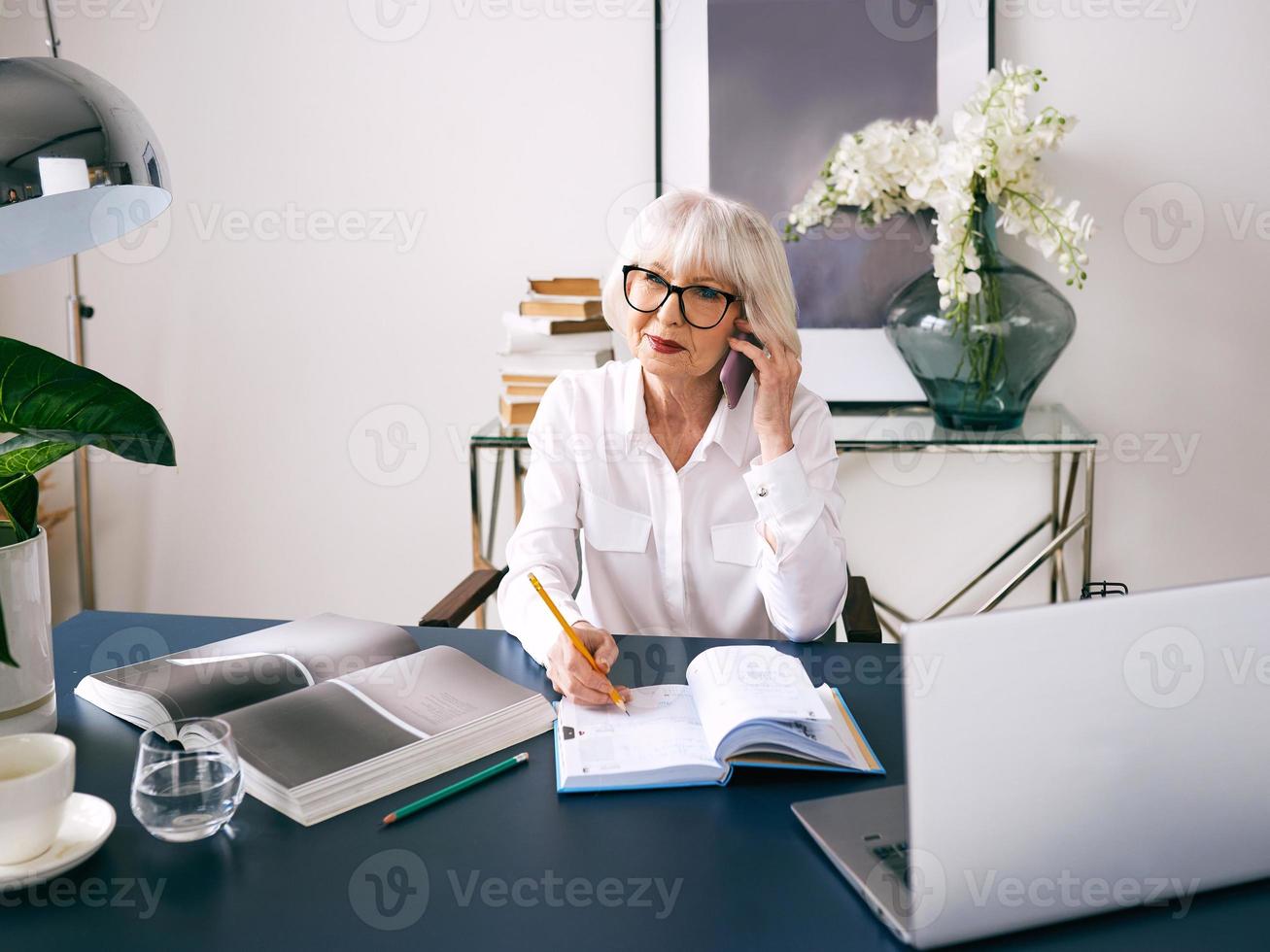 müde senior schöne graue Haare Frau in weißer Bluse am Laptop im Büro arbeiten. Arbeit, Senioren, Probleme, Lösung finden, Konzept erleben foto