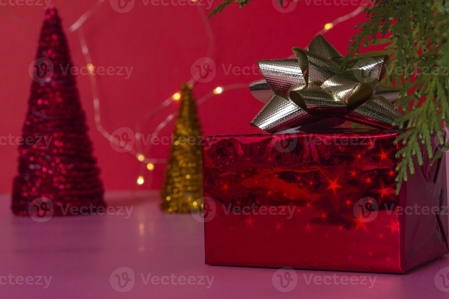 ein fabelhaftes Geschenk in einer roten Schachtel mit einem goldenen Band unter dem Weihnachtsbaum auf einem rosa Hintergrund. Silvester und Weihnachten. Platz kopieren foto