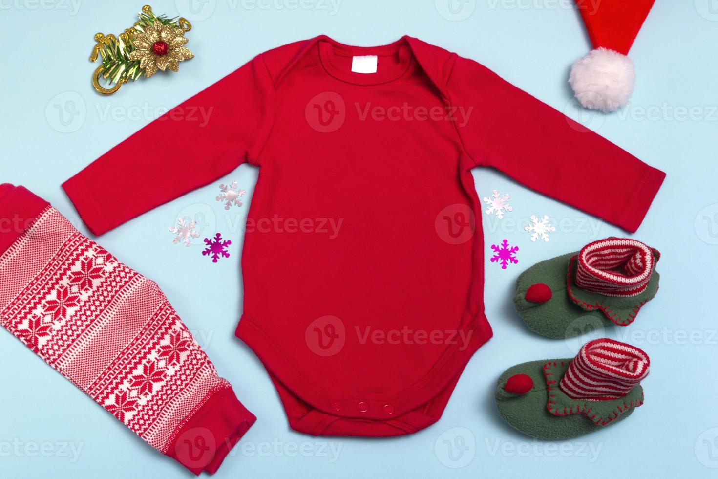 mockup des roten langarmbodysuits des neuen jahres auf blauem hintergrund, verziert mit socken, roten hosen und weihnachtsbaumschmuck, draufsicht. Mockup für die Gestaltung und Platzierung von Logos foto