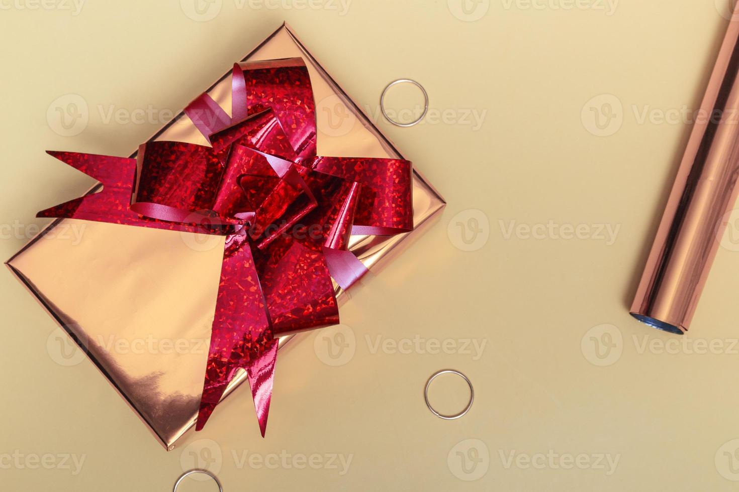 schöne goldene Geschenkbox mit roter Schleife und Ornamenten auf farbigem Hintergrund foto