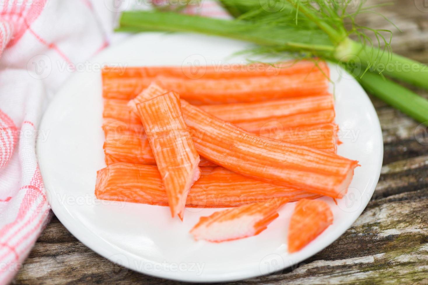 Krabbenstäbchen in Scheiben geschnitten auf weißem Teller und Gemüse, frische Krabbenstäbchen Surimi bereit, japanisches Essen zu essen. foto