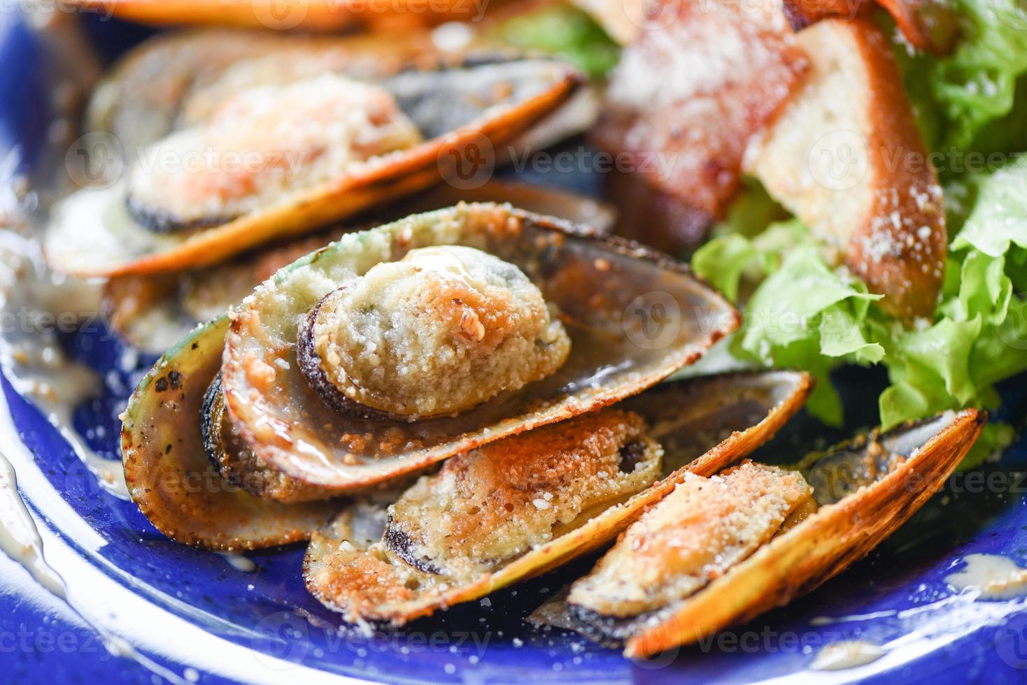 Schalentiere Meeresfrüchteplatte frische Muscheln mit Käse gebacken Abendessen gekocht - gegrillte Muschelschale Schinken Gemüse und Sauce Meeresfrüchte auf dem Tisch serviert foto